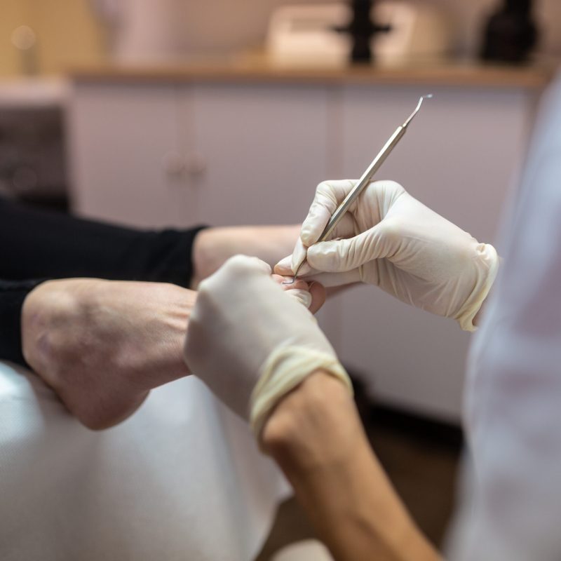 Closeup of removing cuticle from toenails in a pedicure treatment.