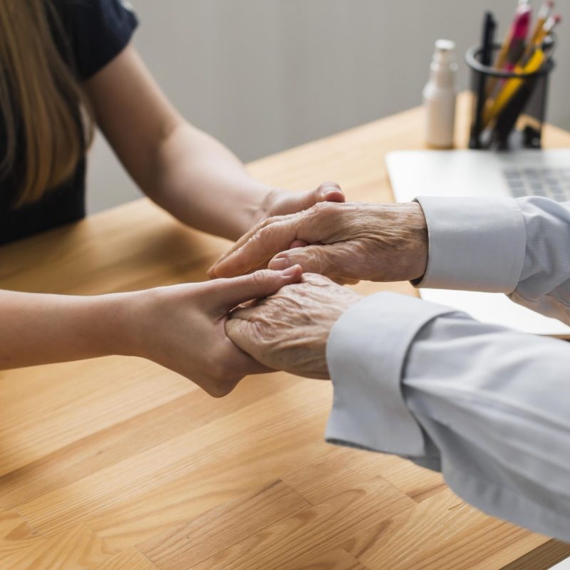 enfermeira-segurando-as-maos-de-homem-senior